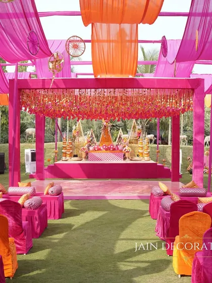 An explosion of color for an outdoor Mehndi. I used flowing drapes in shades of pink and orange to create a festive canopy, with a grand stage and comfortable floor seating for a relaxed, celebratory vibe.