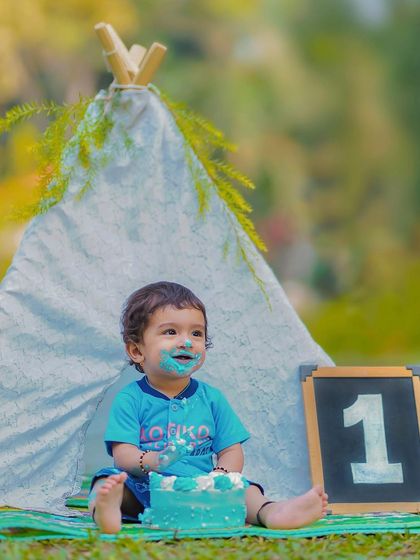 The aftermath of a successful cake smash! The pure happiness and blue frosting on his face make for an unforgettable first birthday photograph.