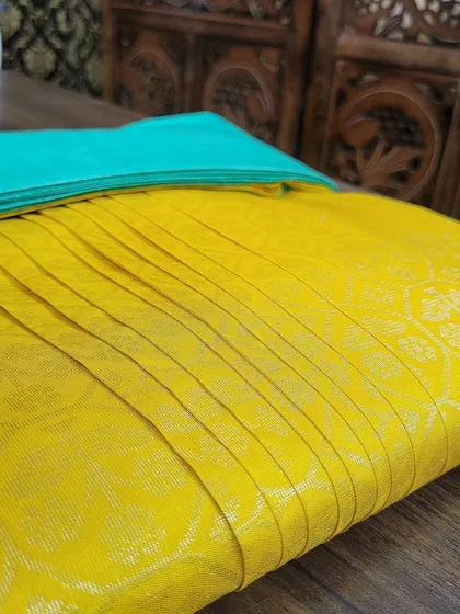 A bright yellow silk saree, expertly box-folded. This is the perfect solution for attending destination weddings or functions where you need to look your best without a hassle.