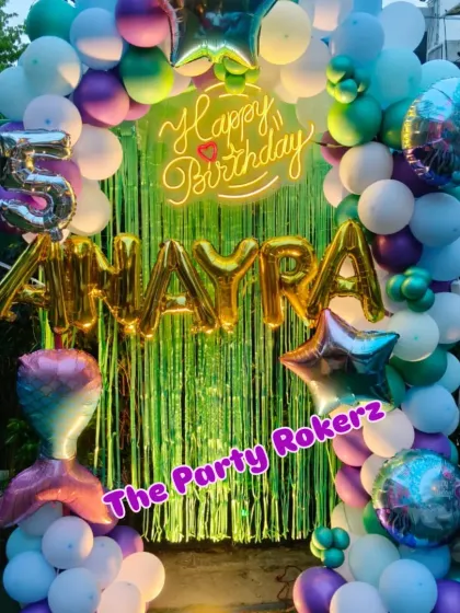 An underwater adventure with this Mermaid-themed 5th birthday. The decor features a green shimmer backdrop, a balloon arch in ocean colors, and a mermaid tail foil balloon.