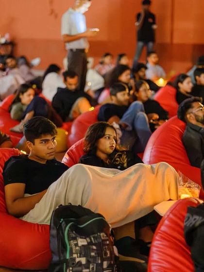 Friends getting cozy under a blanket for a rooftop movie night in Bangalore. You can bring your own snacks and blankets to make the experience feel just like home, only better.