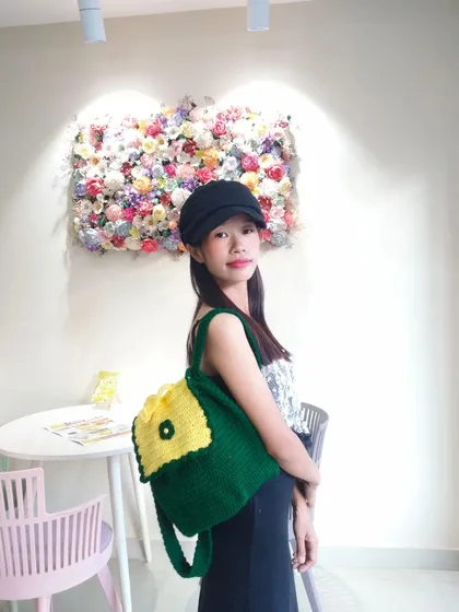 A custom-made backpack in green and yellow, modeled to show its size and how it's worn. Perfect for students or for a casual day out.