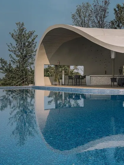 The curved form of the Aqua Pool & Spa is reflected in the water, creating a continuous, flowing shape that echoes the surrounding landscape.