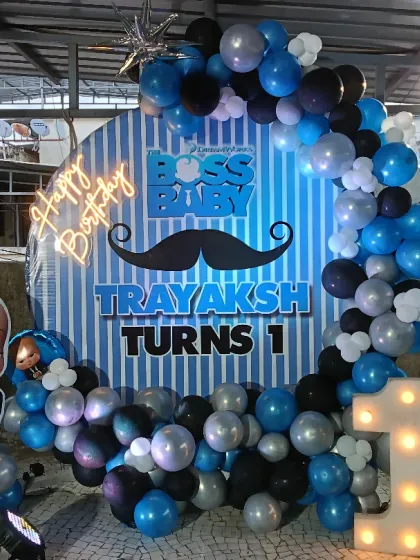 Who's the boss? This Boss Baby theme is perfect for a first birthday. It features a circular backdrop with character cutouts, a blue, black, and silver balloon garland, and a light-up number "1".