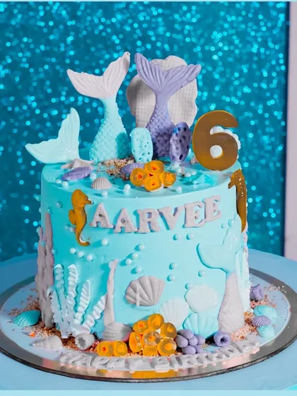 The centerpiece of a magical underwater celebration. This custom-designed mermaid theme cake features intricate details like seahorses, coral, and shimmering mermaid tails, perfectly matching the party's 'Under the Sea' decor for a 6th birthday.