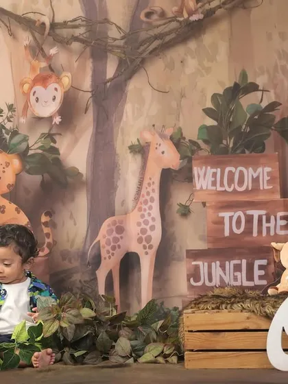 The little explorer playing with props in our "Welcome to the Jungle" setup, perfect for a first birthday adventure.