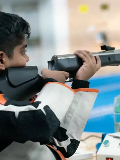 A young rifle shooter in his competition gear, concentrating on his target. Our youth program is designed to build a strong foundation in shooting fundamentals.