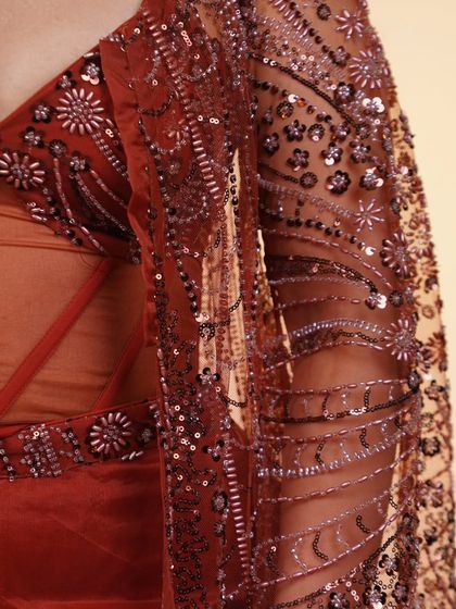 A close-up of the intricate beadwork on the sleeve of our rust-colored Indo-Western outfit. The detail is what makes our pieces special.