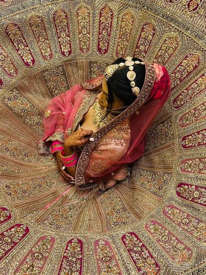 A stunning top-down shot of a bride in her lehenga. This artistic angle showcases the incredible circular flare and detailed embroidery of the skirt, creating a piece of art.