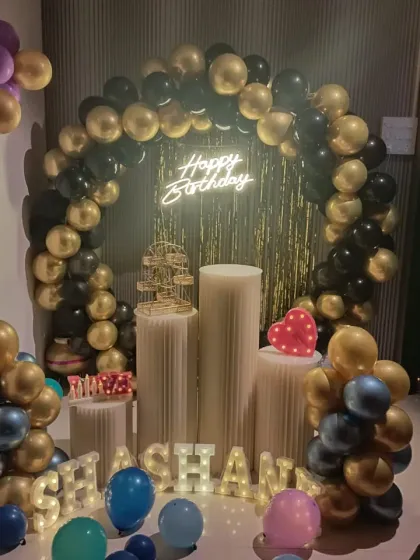 A classic black and gold balloon arch for a sophisticated birthday party. The name "SHASHANK" is displayed in light-up letters for a personal touch.