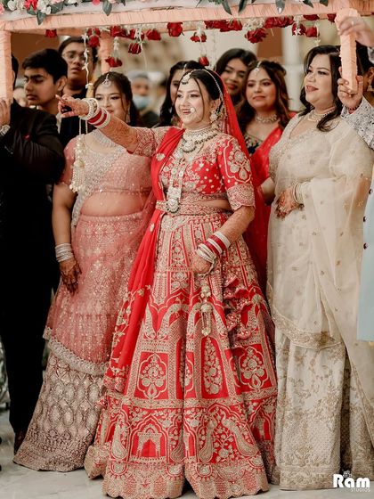 A beautiful shot of the bride during her entrance under a 'phoolon ki chadar,' surrounded by her loving family.