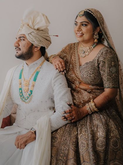 A classic seated portrait with the couple looking away, exuding an aura of royal elegance in their stunning wedding attire.