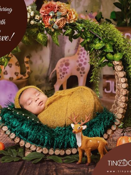 Welcome to the jungle! This enchanting woodland theme features a newborn sleeping in a rustic wreath, surrounded by greenery and adorable animal figures like a giraffe and a deer.