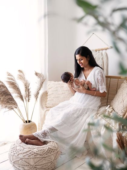 A mother sits peacefully, holding her newborn baby. This lifestyle portrait captures the quiet beauty of the fourth trimester.