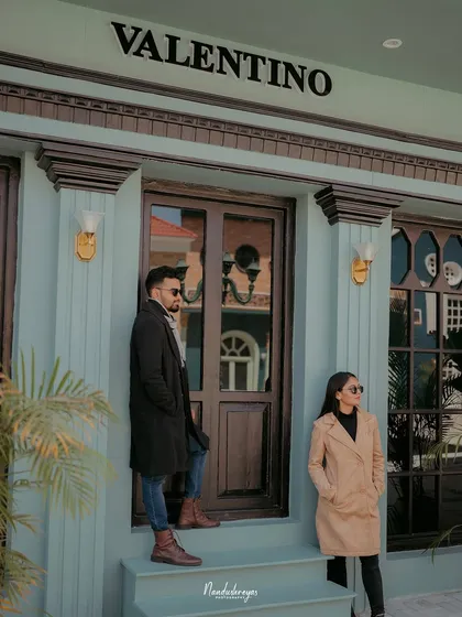 A fashionable shot of a couple posing on the steps of a chic, urban storefront.