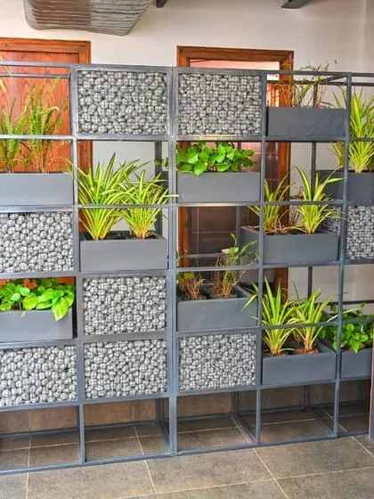 This custom partition at The Fixx in Bangalore showcases a creative approach to dividing a space. We designed a modular grid that combines living plants with natural stone elements, acting as both a functional separator and a unique piece of biophilic art.