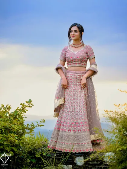 A wide shot of the model against a beautiful sky, showcasing the full bridal look in a natural, scenic location.
