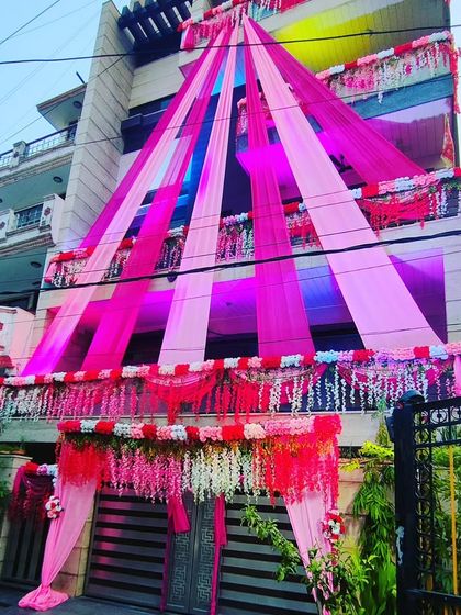 The pink-themed house decoration seen from a different angle, showcasing the cascading drapes and floral details on the balcony.