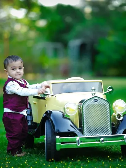 A candid moment as the toddler interacts with his toy car in the beautiful green surroundings.