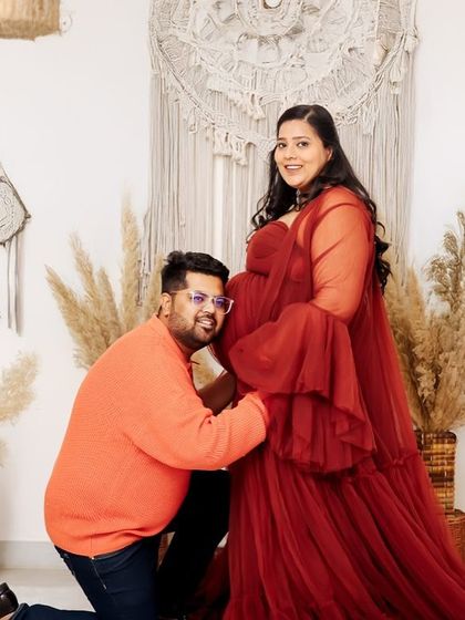 A playful and loving pose where the partner kneels to listen to the baby bump. This is captured in our versatile boho studio, filled with natural light and textures.