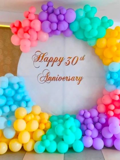 A colorful balloon decoration for a 30th anniversary. The pastel rainbow balloon arch creates a cheerful and celebratory backdrop.