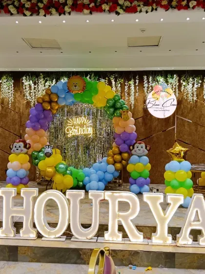 We transformed this venue into a jungle safari for a first birthday party. The setup includes a large balloon ring, monkey-themed balloon pillars, and large marquee letters for the birthday boy's name, creating a perfect photo backdrop.