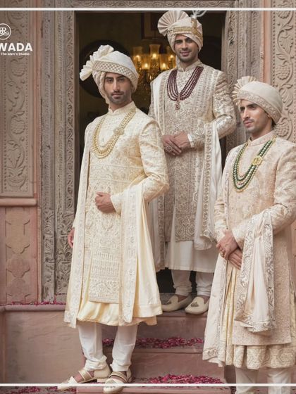 The Shauhar collection is about heritage reimagined. This image shows three grooms on a staircase, their sherwanis reflecting a blend of traditional motifs and modern silhouettes.