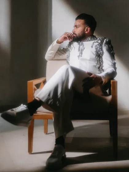 The groom, looking thoughtful and dapper in a moment of quiet reflection. The dramatic side lighting highlights the texture and detail of his stylish outfit.