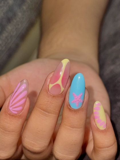 A close-up of the beach-themed nails. The details on the shell and the abstract water patterns give off the perfect tropical vibe.