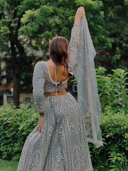The back of this grey lehenga is just as beautiful, with a deep back and delicate ties. The net dupatta adds to the elegance.