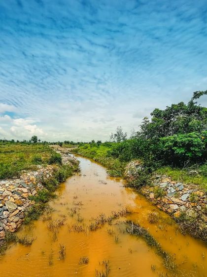 A man-made stream under a cloudy sky. We design our water systems to be both functional and beautiful, integrating them seamlessly into the natural landscape.
