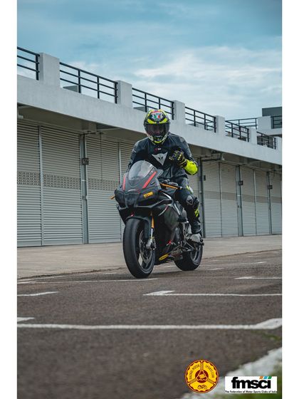 A rider on an Aprilia RSV4 giving a wave as they head out of the pit lane. The vibe is always friendly and supportive.