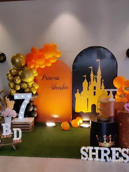 A unique princess-themed seventh birthday with a black and orange color scheme. The setup features a castle silhouette backdrop and a large light-up number '7'.