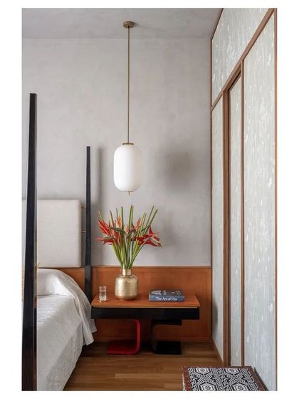 A close-up of the bedside, with a hanging pendant light and custom side table, showcasing the Channapatna-inspired design.