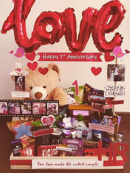 A classic first anniversary hamper that's all about love. It features a large teddy bear, a 'LOVE' balloon, photo film strips, and a huge assortment of chocolates and snacks to celebrate the milestone.