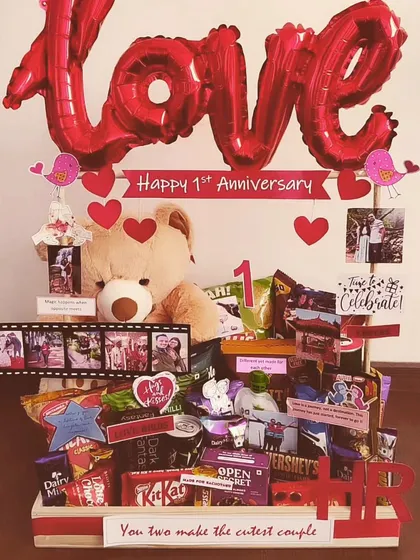 A classic first anniversary hamper that's all about love. It features a large teddy bear, a 'LOVE' balloon, photo film strips, and a huge assortment of chocolates and snacks to celebrate the milestone.