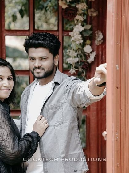 A couple poses in a red telephone booth, creating a charming and slightly vintage pre-wedding photo.