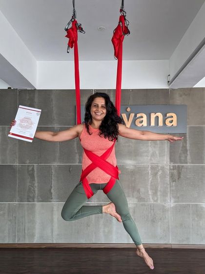 A graduate shows off her strength and flexibility, holding her certificate while suspended in a dynamic pose.