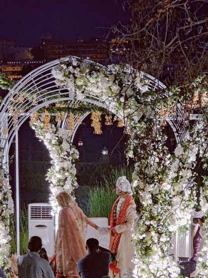 The couple during their wedding ceremony at a grand, lit-up venue. We have the experience to manage choreography for events of any scale.