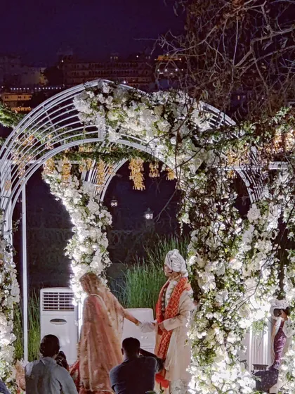 The couple during their wedding ceremony at a grand, lit-up venue. We have the experience to manage choreography for events of any scale.