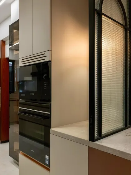 This little nook, formed between the appliance unit and a glass divider, became the perfect pause point. With plug points and a warm lamp, it’s an ideal spot for the kettle and toaster, turning an accidental space into a functional corner.