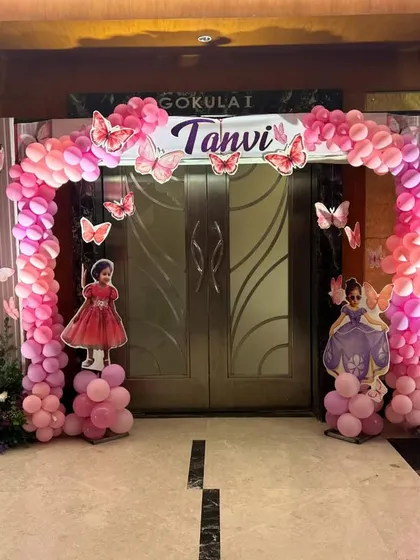 A magical butterfly themed entrance arch for a child's birthday. A lush pink balloon arch adorned with butterflies frames the doorway, with large, elegant butterfly wings creating an immersive welcome for guests.