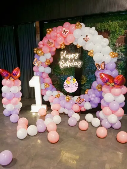 An enchanting butterfly-themed birthday with a pastel balloon ring, neon sign, and matching balloon pillars.