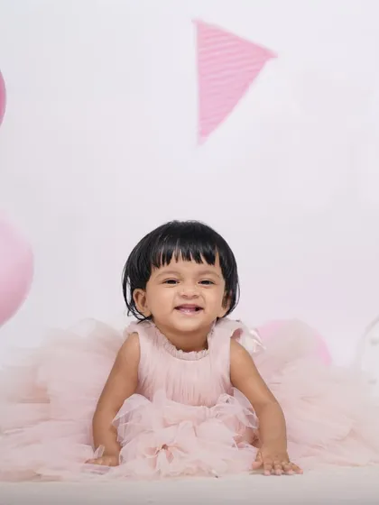 A simple and sweet studio session for a first birthday. Dressed in a beautiful pink tulle dress, this little one's smile is the main highlight against a clean, bright background with matching balloons.