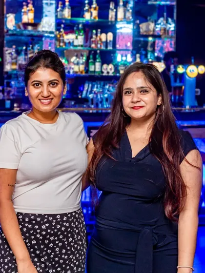 Two friends posing in front of the bar.