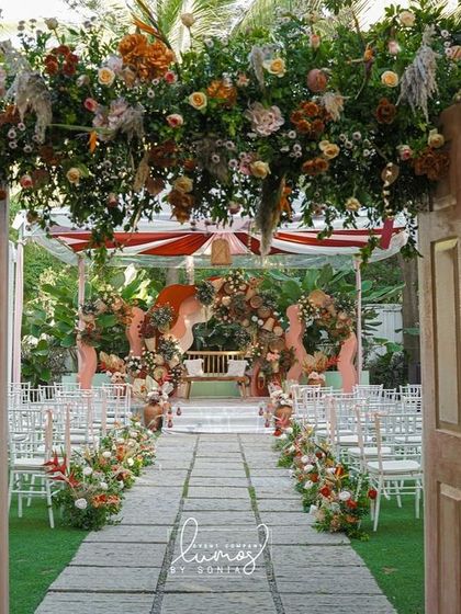 A stunning wedding entrance featuring two large doors adorned with an arch of terracotta and blush florals. This design creates a beautiful and welcoming gateway for guests.