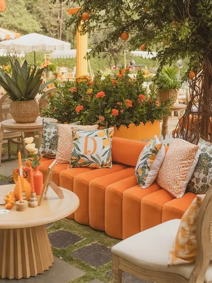 A curved orange velvet sofa is decorated with custom-printed cushions, creating a chic and comfortable lounge spot.