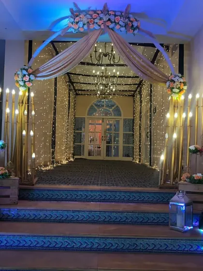 A warm and inviting entrance tunnel created with flowing drapes and strings of fairy lights. We added rustic wooden crates, lanterns, and floral arrangements at the sides to complete the charming look.