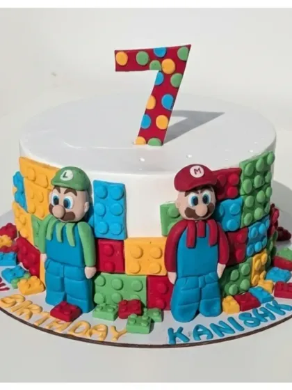 A creative crossover of Super Mario and LEGO for a 7th birthday. This soft eggless truffle cake features handmade fondant figures of Mario and Luigi surrounded by colorful, edible bricks.