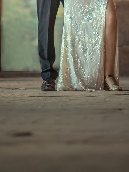 A creative, low-angle shot focusing on the couple's feet and the elegant details of the bride-to-be's sequined dress.